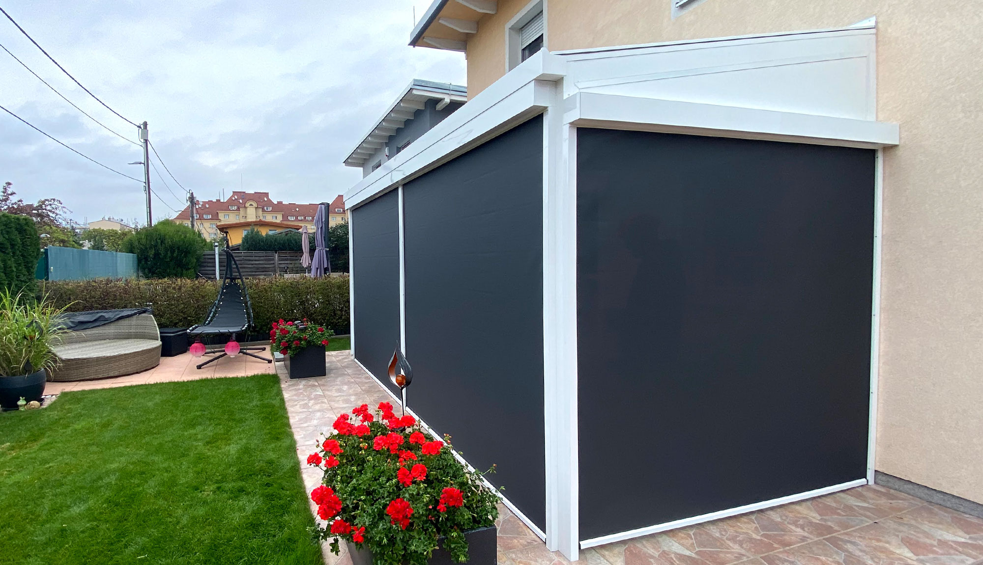 Schwarze geschlossene Senkrechtmarkisen auf einer weißen Terrassenüberdachung. Seitliche Ansicht.