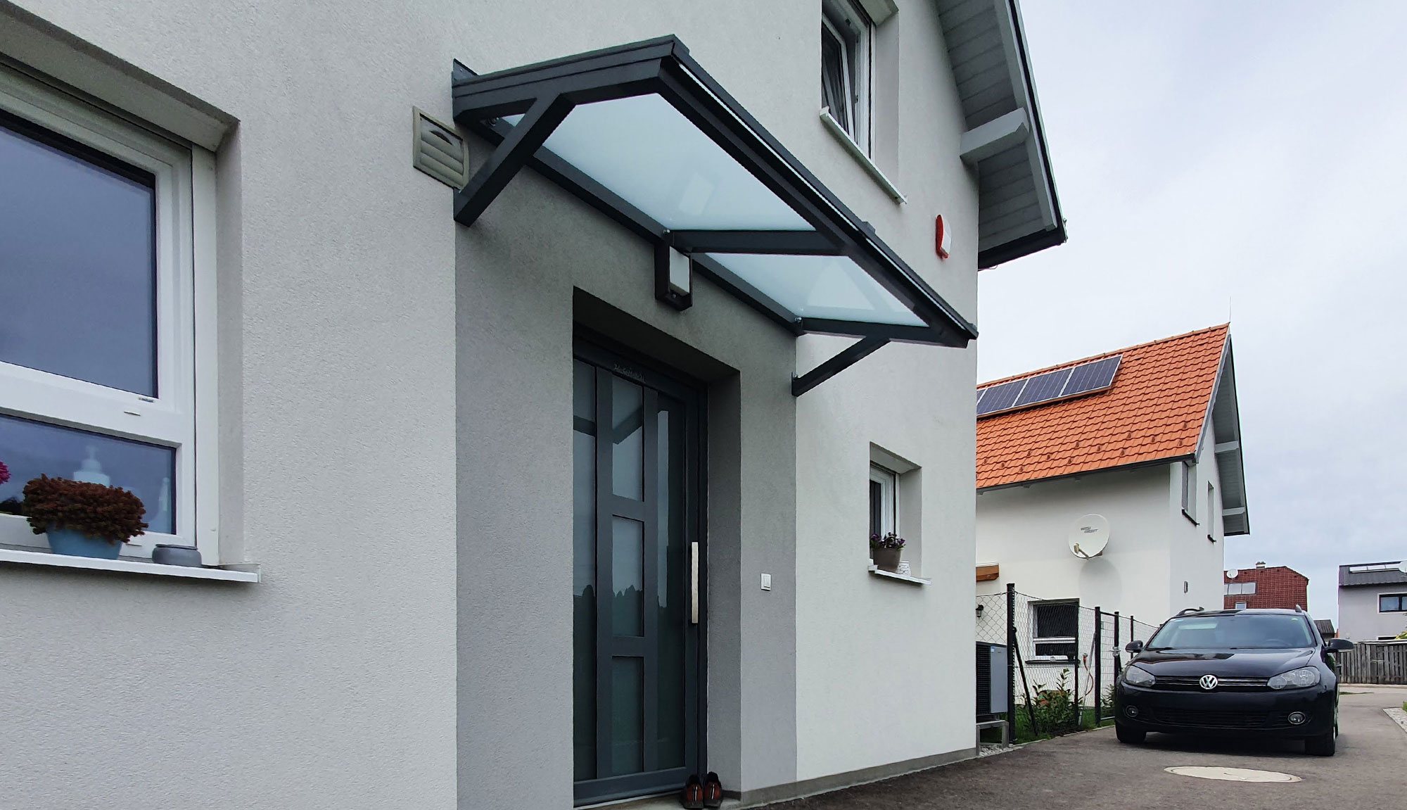 Moderne Eingangsüberdachung ohne Steher mit opaler Glaseindeckung an einem modernen Einfamilienhaus.
