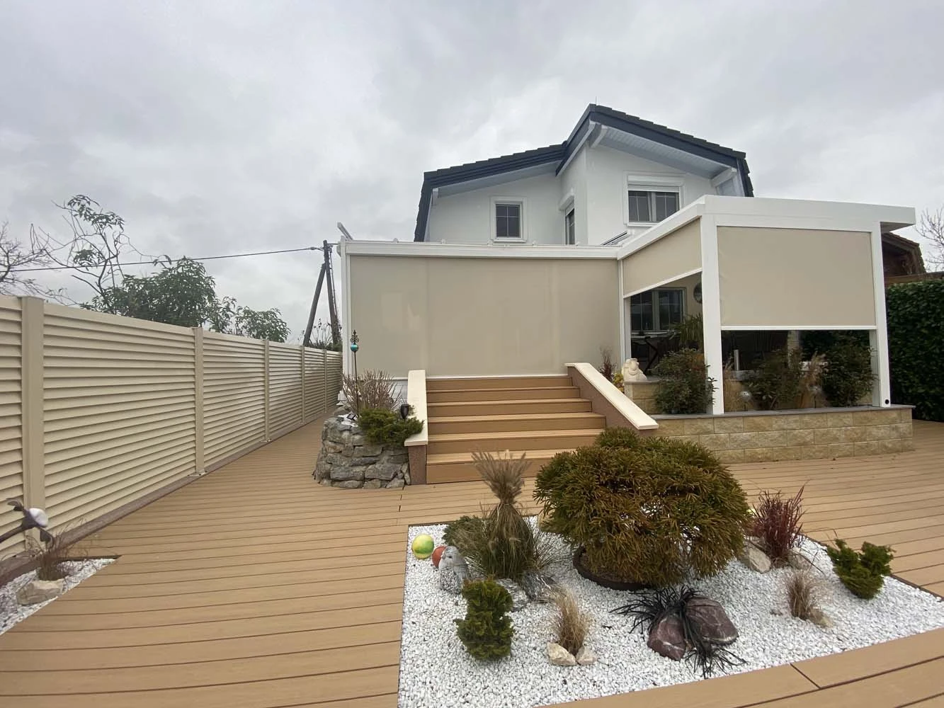 Ein weißes Lamellendach mit Senkrechtmarkisen.